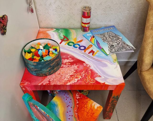 Colțul de joacă, cu o masă colorată, piese de construit, creioane colorate și cărți de colorat