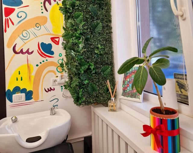 Colțul cu chiuveta, peretele pictat, planta și ghiveciul îmbrăcat în creioane colorate